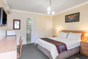 1 dormitorio con cama, escritorio y cocina en Best Western Governor Gipps Motor Inn en Traralgon