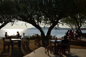 a group of people sitting at tables near the water at Hotel Votsala in Pyrgi Thermis