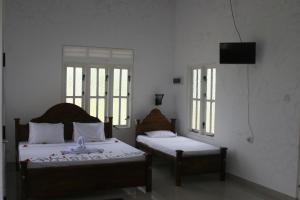 a bedroom with two beds and two windows at Ritigala Lodge in Habarana