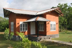 a small orange house with a white door at Ritigala Lodge in Habarana