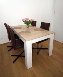 a table with chairs and a vase of flowers on it at Kurzzeit-Apartment Nussdorf in Vienna