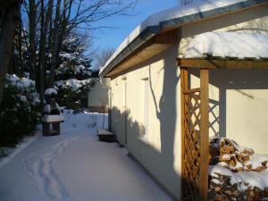 a snow covered sidewalk next to a building with a bell at Ferienhaus 2 Am Eichenberg in Blankenburg +4 photos