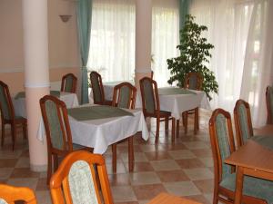 un comedor con mesas, sillas y ventanas en Korona Panzió, en Debrecen