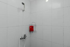una ducha con una caja roja en una pared blanca en RedDoorz Plus @ Pasar Baru, en Yakarta