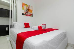 a bedroom with a large white bed with a red blanket at RedDoorz Plus @ Pasar Baru in Jakarta