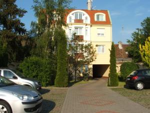 una casa amarilla con techo rojo y coches aparcados delante en Korona Panzió en Debrecen