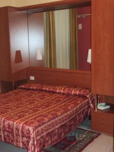 モンテカティーニ・テルメにあるHotel Innocentiの大きな鏡付きのベッドが備わるホテルルームです。
