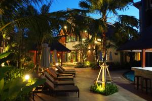 un patio del complejo con sillas y sombrillas por la noche en Hula Hula Resort, Ao Nang -SHA Extra Plus, en Ao Nang Beach