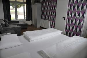 a bedroom with two white beds and a couch at aQuarium City Vendégház in Abádszalók +15 photos