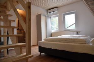 a bedroom with a bed and a wooden staircase at aQuarium City Vendégház in Abádszalók