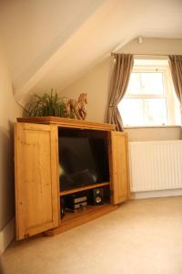 a wooden entertainment center with a television in a attic at Cuilcagh Luxury Apartment in Enniskillen