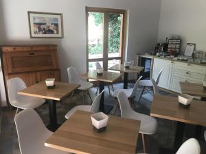 a restaurant with wooden tables and white chairs at Wingbay B&B in Portorož