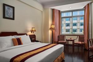 Phnom Penh Hotel في بنوم بنه: غرفه فندقيه بسرير ونافذه