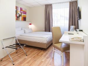 ein Hotelzimmer mit einem Bett und einem Schreibtisch in der Unterkunft Hotel am Schloß Köpenick by Golden Tulip in Berlin
