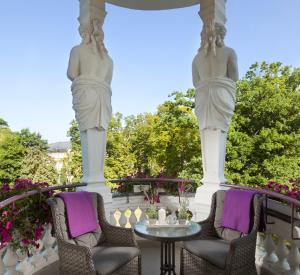 zwei Statuen auf einer Veranda mit Stühlen und einem Tisch in der Unterkunft Imperial Spa & Kurhotel in Franzensbad