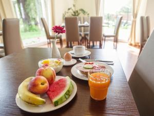 a table with two plates of fruit and orange juice at Hotel am Schloß Köpenick by Golden Tulip in Berlin