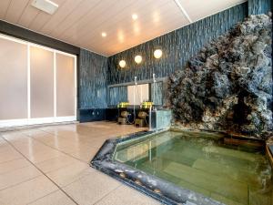 a pool of water in a room with a rock wall at TKP Lectore Atami Momoyama in Atami