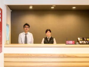 two people sitting behind a counter in a room at TKP Lectore Atami Momoyama in Atami