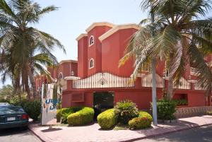 a red building with palm trees in front of it at فلل رويال ان in Jeddah