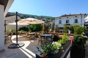 eine Terrasse mit Tischen, Stühlen und einem Sonnenschirm in der Unterkunft Hotel Tiffany in Prizren