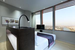 a bedroom with a large bed and a large window at Eurostars Torre Sevilla in Seville