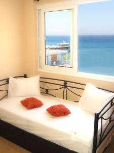 1 cama con 2 almohadas rojas frente a una ventana en Dorana Apartments & Trekking Hotel en Diafani