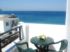 una mesa y sillas en un balcón con vistas al océano en Dorana Apartments & Trekking Hotel, en Diafani