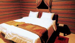 a neatly made bed in a hotel room at Beyond Wadi Rum Camp in Wadi Rum