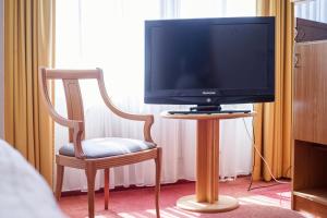 a tv sitting on a table next to a chair at Hotel Dänischer Hof Altenholz by Tulip Inn in Altenholz
