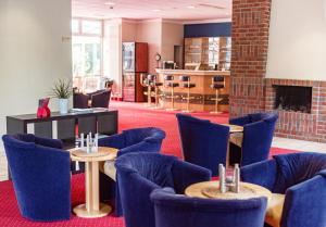 a waiting room with blue chairs and tables and a fireplace at Hotel Dänischer Hof Altenholz by Tulip Inn in Altenholz +29 photos