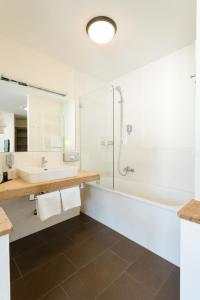 een badkamer met een douche, een wastafel en een bad bij Hotel Saliter Hof in Saalfelden am Steinernen Meer
