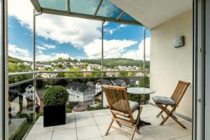 balcón con mesa, sillas y vistas en AUSZEIT - Art & Design Ferienapartment, en Bad Endbach