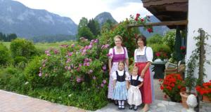 un grupo de tres mujeres y dos niños parados frente a las flores en Pension mit Bergblick in Inzell en Inzell