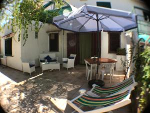 a patio with a table and chairs and an umbrella at Casa Bianca Rais Gerbi in Finale