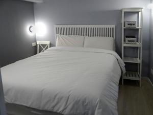 a bedroom with a white bed with two shelves at Martina Lapiko in Ea