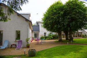 a yard with purple chairs and a tree and a house at Le petit manoir in Farceaux