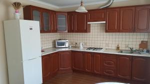a kitchen with wooden cabinets and a white refrigerator at Celebrity in Kamianets-Podilskyi
