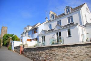 a large white house on a stone wall at Waves - Duplex Apartment Stoke Fleming in Stoke Fleming