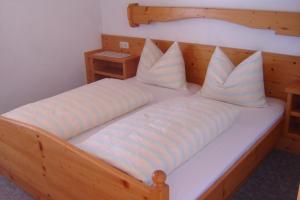 ケセンにあるGästehaus Grünbacherの大きな木製ベッド(白いシーツ、枕付)