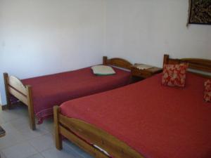 two beds in a room with red sheets at Casablanca in Chascomús
