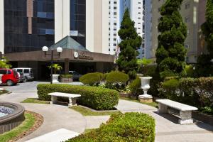 a park with benches and bushes in a city at Le Premier Apartamentos in São Paulo