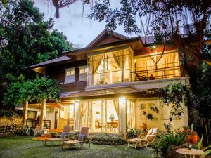 Casa grande con ventanas y sillas en el patio en Banyan House Samui bed and breakfast (Adult Only), en Chaweng