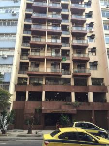 un coche amarillo estacionado frente a un edificio alto en Ipanema Magnifico, en Río de Janeiro