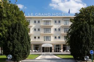 a large white hotel with trees in front of it at Hôtel Barrière le Grand Hôtel Enghien-les-Bains in Enghien-les-Bains