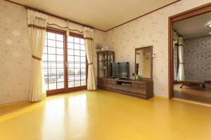 a living room with a television and a large window at Nuyoungnayoung Pension in Seogwipo