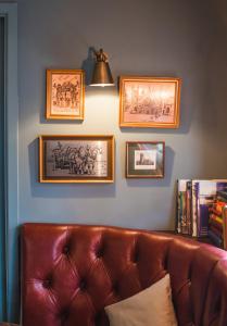 a brown leather couch in a room with pictures on the wall at The Waterman in Cambridge