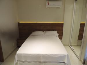 a bedroom with a white bed with a wooden headboard at Liberty - CA - Lago Norte in Brasília