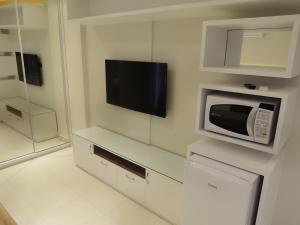 a kitchen with a microwave and a tv on the wall at Liberty - CA - Lago Norte in Brasília