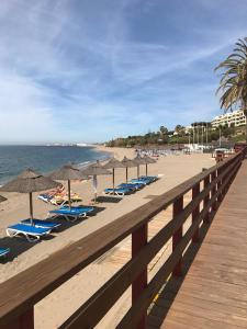 una fila de sillas de playa y sombrillas en una playa en apartment by the beach, en Mijas Costa