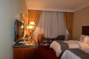 a hotel room with two beds and a desk with a mirror at Hayah Grand Hotel Ex Al Jaad Madinah Hotel in Medina